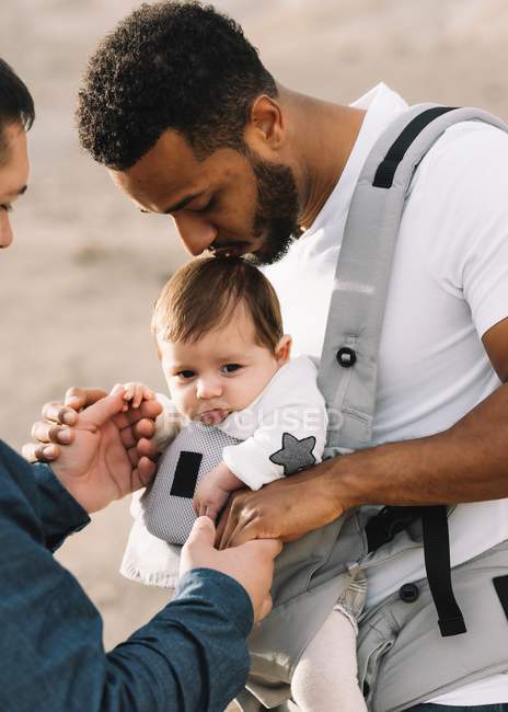 Pais multirraciais abraçando pequeno bebê ao ar livre — Fotografia de Stock
