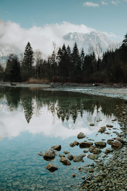 Paisagem de tirar o fôlego de calmo lago transparente cercado por montanhas nevadas e floresta escura em Hallstatt — Fotografia de Stock