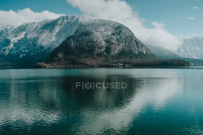 Неймовірний краєвид хвилястого озера, що відбиває яскраве хмарне небо і сніжні гори в Галстаті. — стокове фото