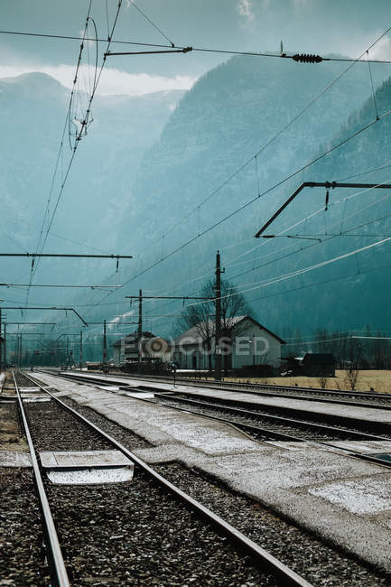 Ferrovia vazia e fios elétricos passando por montanhas se afogando em neblina nebulosa em Hallstatt — Fotografia de Stock