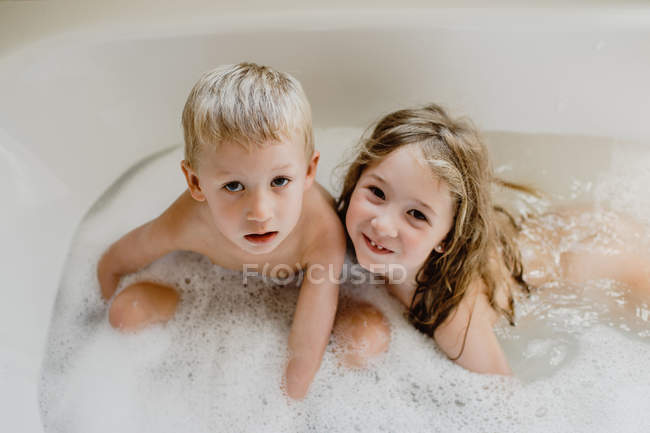 Niños divertidos jugando con espuma en el baño - foto de stock