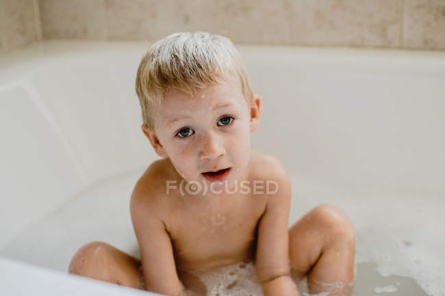 Ragazzo carino che gioca con la schiuma nel bagno — Foto stock