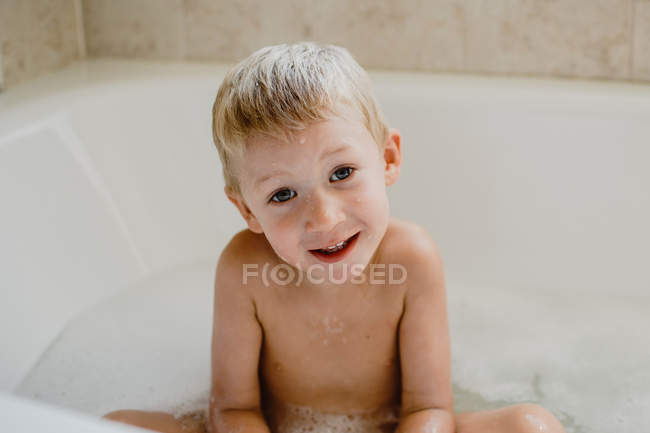 Lindo niño jugando con espuma en el baño - foto de stock