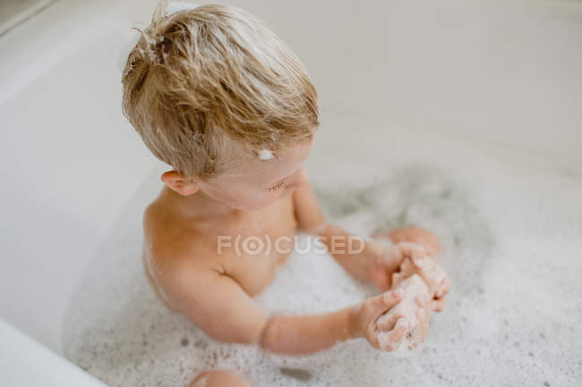Cute kid playing with foam in bath — Stock Photo