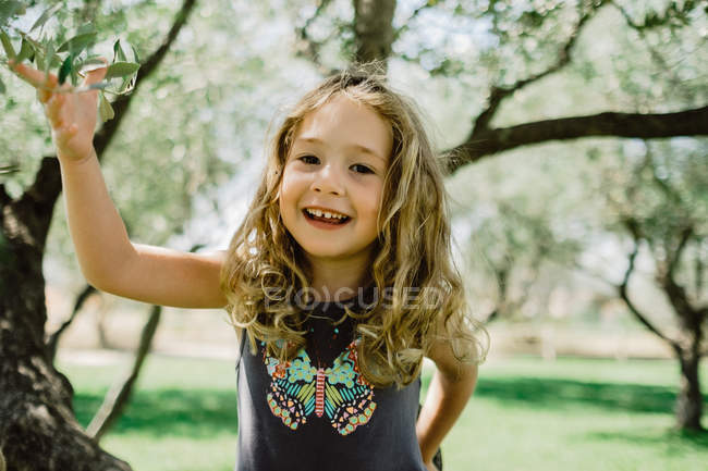 Souriante fille grimpant arbre dans la journée ensoleillée — Photo de stock