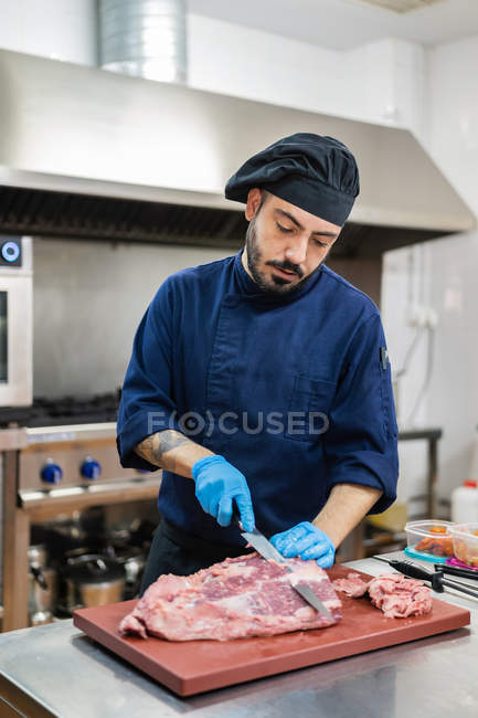 Chef coupant la viande dans la cuisine — Photo de stock