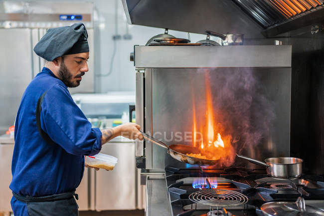 Кухар готує з полум'ям на сковороді — стокове фото
