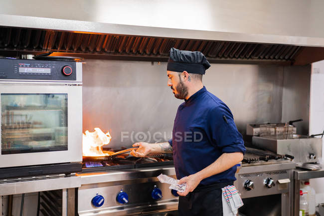 Cozinha Chef com chama na frigideira — Fotografia de Stock