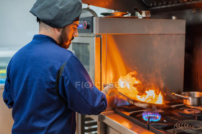Chef cooking with flame in frying pan — Stock Photo