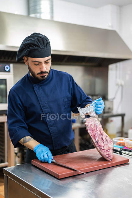 Cook with large piece of raw meat in kitchen — Stock Photo