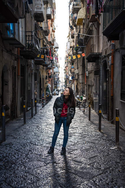Donna in abiti caldi esplorare stretta strada di pietra blocco tra vecchi edifici a Quartiere Spagnolo a Napoli — Foto stock