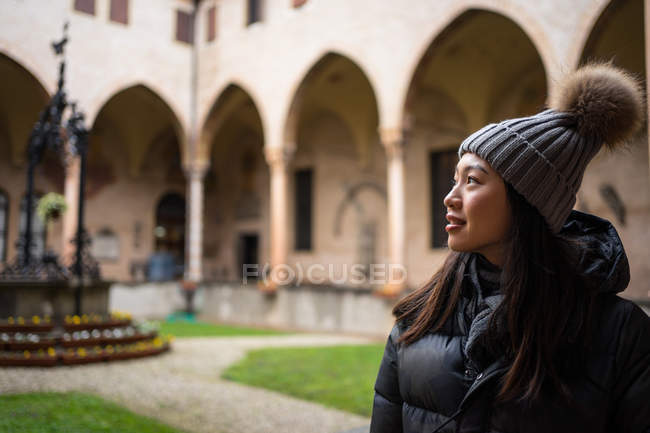 Curious resting Asian woman in warm clothing and hat exploring beautiful ancient Basilica di Sant Antonio di Padova — Stock Photo