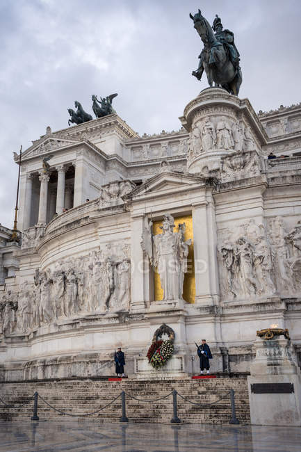 Exterior del antiguo monumento con estatua ecuestre custodiada por soldados en día nublado en Roma, Italia - foto de stock