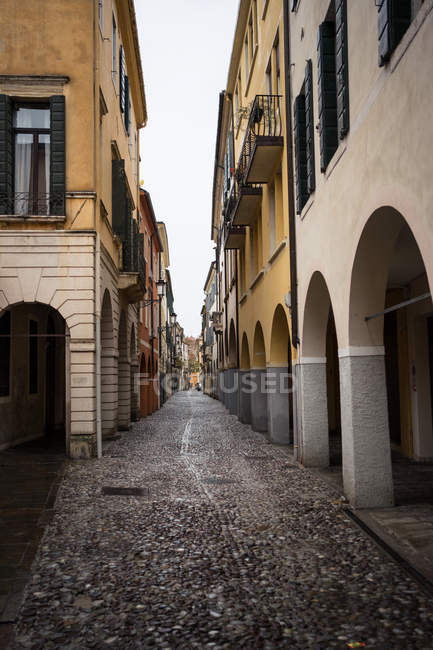 Narrow street with cobblestone road between old colorful buildings with arcs on cloudy weather at Padova at Italy — Stock Photo