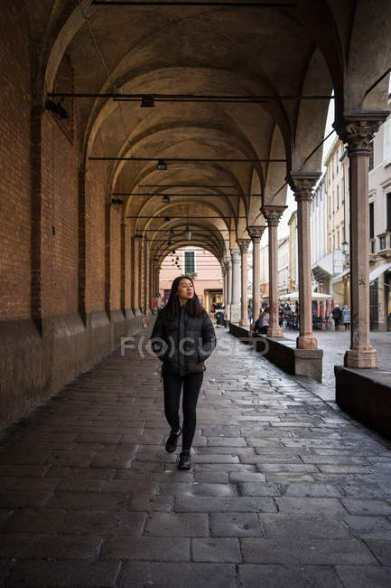 Asian resting female wile exploring ancient streets with rocked roads and buildings with columns and looking away at Papua at Italy — Stock Photo