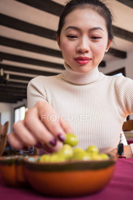 Asian woman eating olives in restaurant — Stock Photo