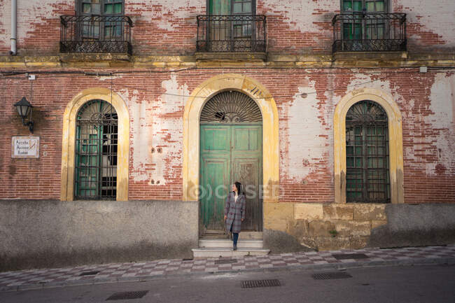 Mujer en la calle con edificio envejecido - foto de stock