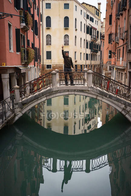 Zufriedener ruhender Mann genießt Urlaub auf kleiner Brücke über Wasserstraße — Stockfoto