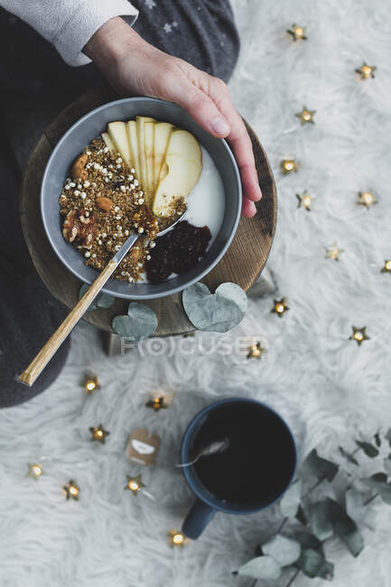 Top view of crop female eating healthy natural nutrition in bowl and drinking cup of tea — Stock Photo
