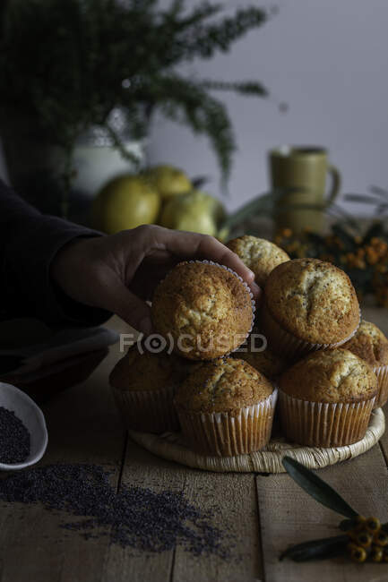 Appetizing fresh baked cupcakes on wicker stand on wooden table decorated with berries lemon and poppy seed for baking — Stock Photo