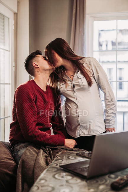 Couple expecting baby kissing at home — стокове фото