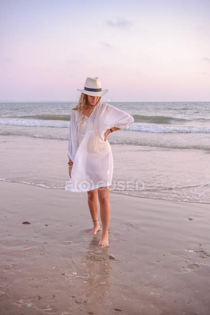 Charmante femme en robe blanche pâle sur la plage ondulée — Photo de stock