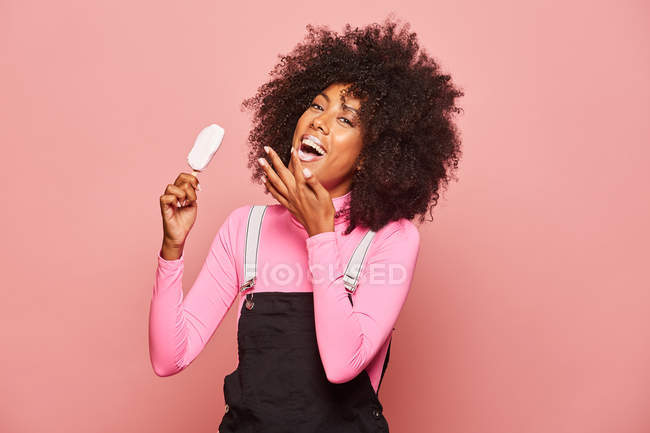 Mujer divertida con helado en palo mirando a la cámara - foto de stock