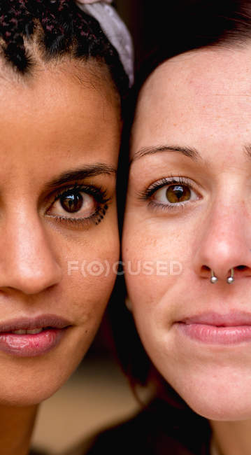 Portrait of crop multiethnic stylish women with earring looking at camera — Stock Photo