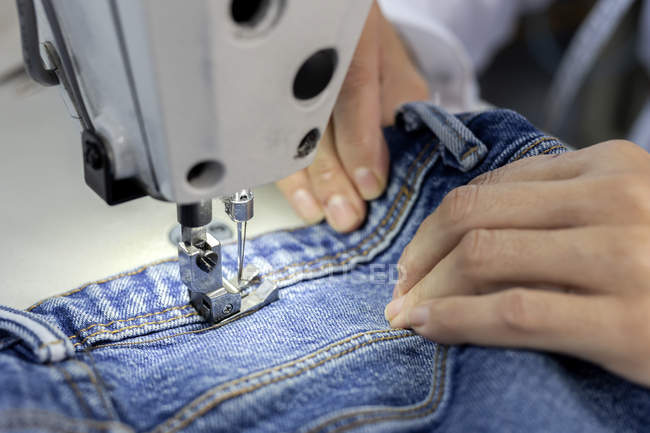 Обрезанный образ рабочего на текстильной фабрике, шитье на промышленной швейной машине. Промышленное производство — стоковое фото