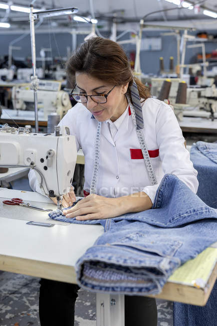 Mulher trabalhadora na costura de fábrica têxtil na máquina de costura industrial. Produção industrial — Fotografia de Stock