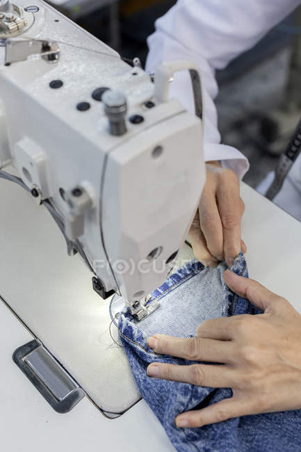 Cropped image of worker in textile factory sewing on industrial sewing machine. Industrial production — Stock Photo