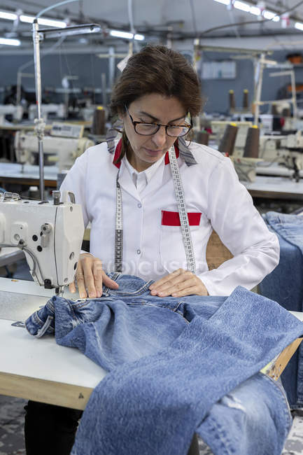 Donna di lavoro nella fabbrica tessile che cuce sulla macchina da cucire industriale. Produzione industriale — Foto stock