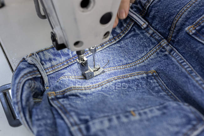 Imagem cortada do trabalhador na costura de fábrica têxtil na máquina de costura industrial. Produção industrial — Fotografia de Stock