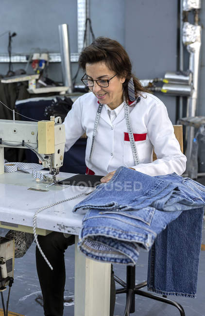 Mujer trabajadora en la costura de fábrica textil en la máquina de coser industrial. Producción industrial - foto de stock