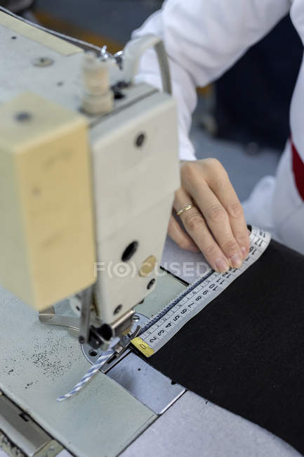 Immagine ritagliata del lavoratore nella fabbrica tessile che cuce sulla macchina da cucire industriale. Produzione industriale — Foto stock