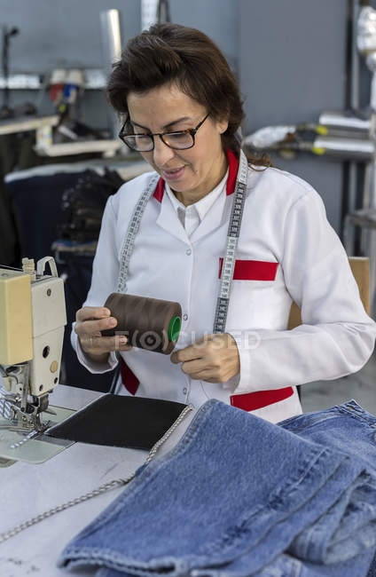 Working woman in textile factory sewing on industrial sewing machine. Industrial production — Stock Photo