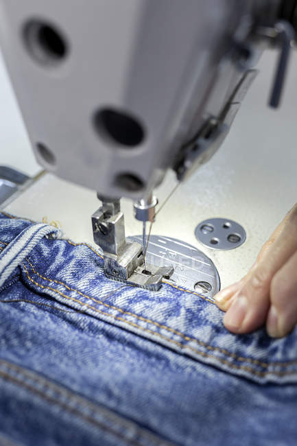 Imagen recortada del trabajador en la costura de fábrica textil en la máquina de coser industrial. Producción industrial - foto de stock