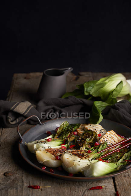 Teller mit leckerem Bok Choy Salat und gebratenem Fisch neben Serviette auf Holztisch — Stockfoto