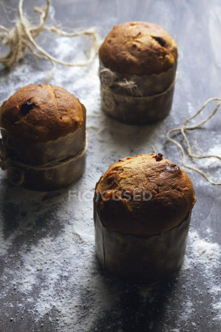 Rustic traditional Christmas panettone cakes with raisins decorated with twine on dusted with flour surface — Stock Photo