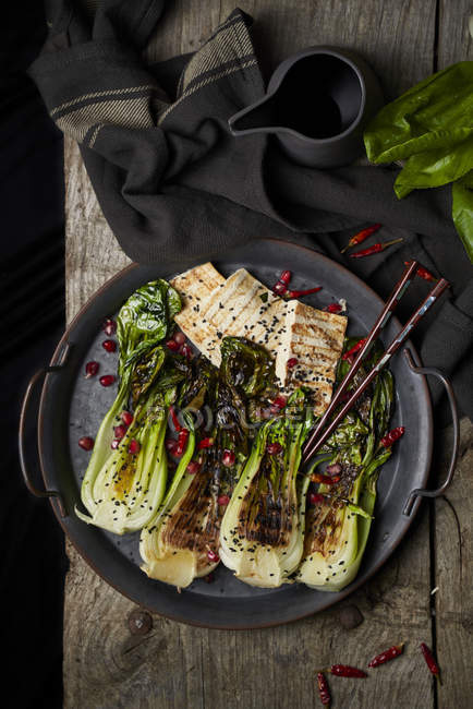Vista dall'alto del piatto con deliziosa insalata bok choy e pesce fritto posizionato vicino al tovagliolo sul tavolo di legno — Foto stock