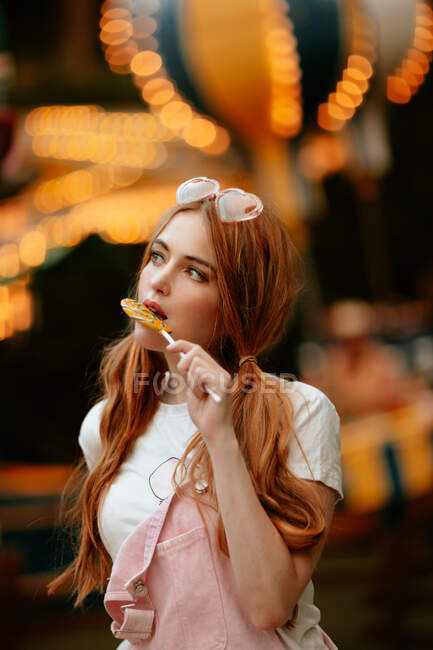 Adolescente donna mangiare lecca-lecca nel parco divertimenti — Foto stock