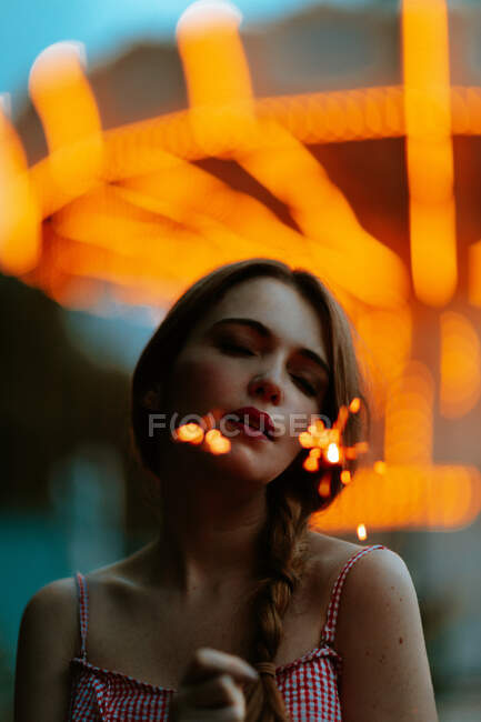 Sinnliche Frau steht im Freizeitpark und hält Wunderkerzen in der Hand — Stockfoto