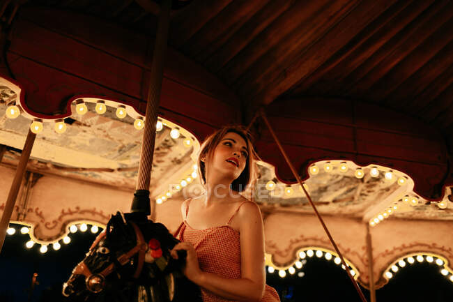 Millennial woman riding carousel horse — Stock Photo