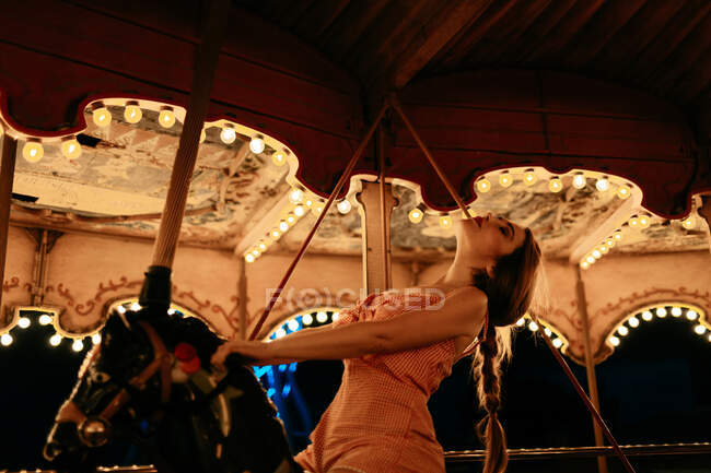Femme millénaire chevauchant cheval carrousel — Photo de stock