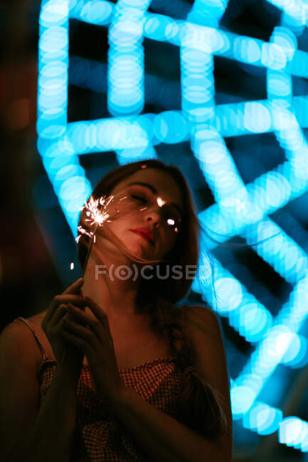 Femme sensuelle debout dans un parc d'attractions et tenant des étincelles — Photo de stock