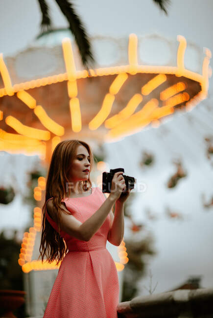 Millennial woman taking picture with camera in amusement park — Stock Photo