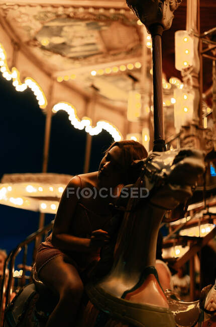 Millennial woman riding carousel horse — Stock Photo