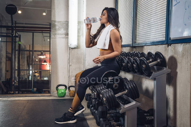 Junge Sportlerin trinkt Wasser in Turnhalle — Stockfoto