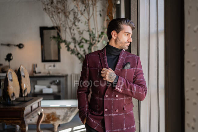 Serious confident elegant man looking out window in country house — Stock Photo