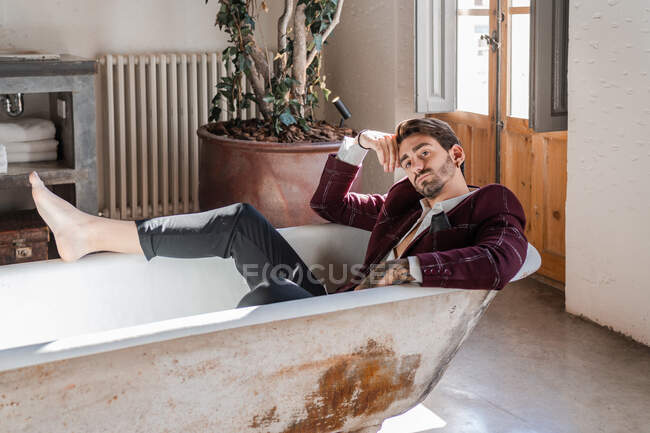 Прохладный элегантный босиком мятежник расслабляется в ванне против винтажного интерьера в загородном доме — стоковое фото
